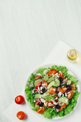 Greek salad with olive oil and tomatoes on a white table side