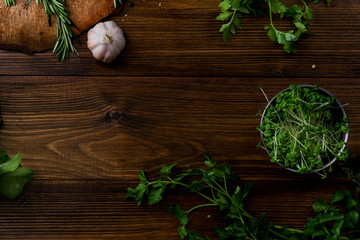Fresh salad ingredients, herbs, tomatoes and garlic on wooden background. Top view with text space. Organic concept.