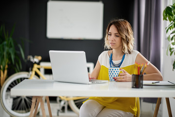 Caucasian businesswoman using laptop computer while sitting in home office. Complementary colors used