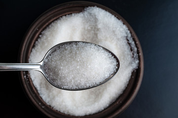 sugar in spoon over a bowl full of sugar