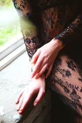 Woman in black lace peignoir sitting on the window sill
