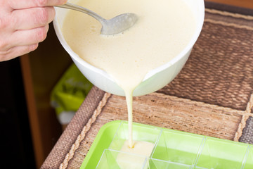 Pouring dough into plastic baking forms.