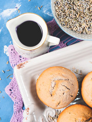 Lavender muffins with ingredients - syrup, milk and flowers on blue textured background. French sweet food brekfast