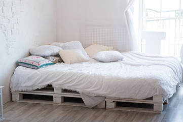 Beautiful white bed on the floor in Loft style