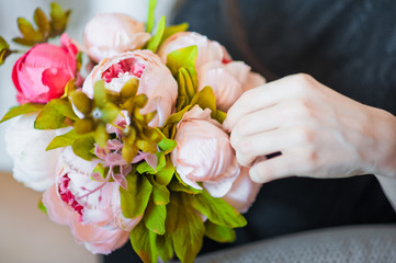 Hands of the girl touch a gentle spring bouquet with peonies