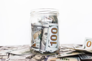 A glass jar with hundred-dollar bills on a white background
