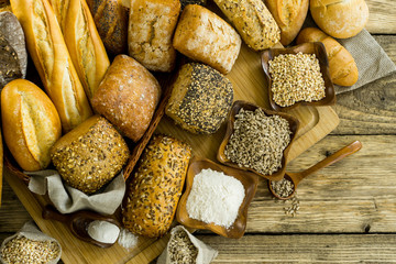 Assortment of baked bread on wooden table background
