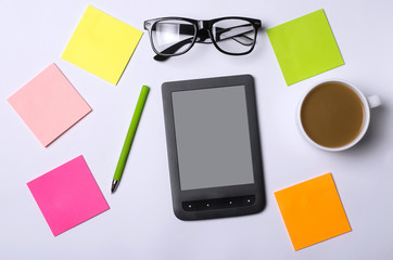 Office table with accessories: a tablet, glasses, pen, paper.