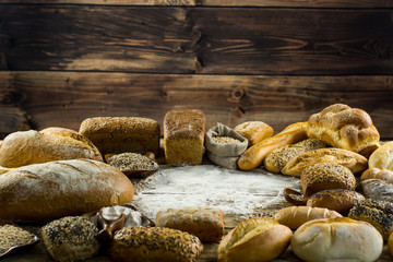 Assortment of baked bread on wooden table background