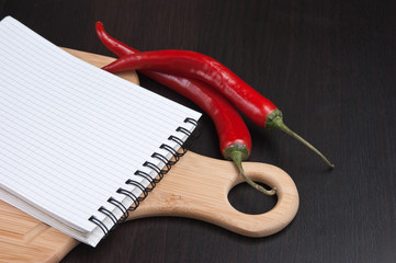 notebook for cooking recipes and red chili peppers