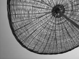 Großer runder Sonnenschirm aus Korbgeflecht im Sommer bei Sonnenschein am Strand von Alacati bei...