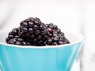 närbild på färska björnbär i turkos skål