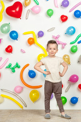 Fototapeta premium boy on a white background with colorful balloons. boy in a tank top and pants on a white background with balloons in the shape of a heart