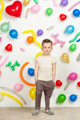 Fototapeta na wymiar boy on a white background with colorful balloons. boy in a tank top and pants on a white background with balloons in the shape of a heart