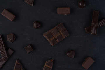 Top view of cracked dark chocolate bar with sweets