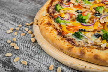 Vegetarian pizza with rosemary and spices on a light wooden background. Italian pizza on a background of green basil and fresh vegetables