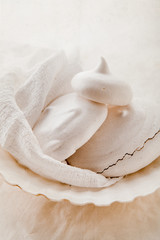 Homemade meringues on ceramic plate and linen fabric