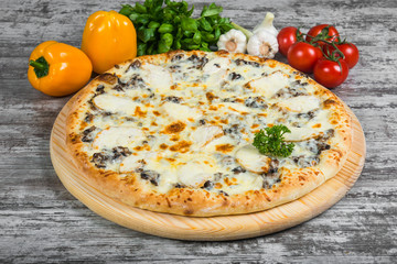 Pizza with chicken and mushrooms with rosemary and spices on a light wooden background. Italian pizza on a background of green basil and fresh vegetables