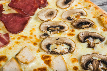 Pizza in four parts, with rosemary and spices on a light wooden background. Italian pizza macro mushrooms
