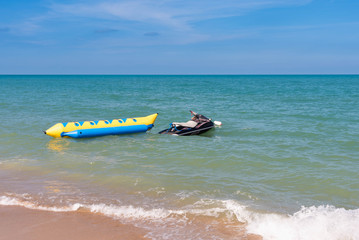 summer holiday by the sea. Beautiful bright blue water and red and white boat and yellow banana boat.