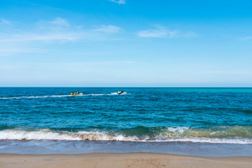 summer holiday by the sea. Beautiful bright blue water and red and white boat and yellow banana boat.