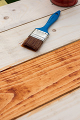 Paintbrush on the fresh painted wooden planks board