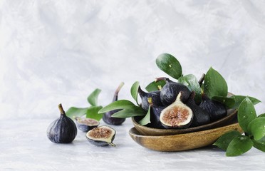 dark blue Fresh figs in a wooden bowl on a white marble table, selective focus
