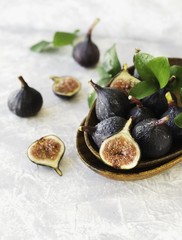 dark blue Fresh figs in a wooden bowl on a white marble table, selective focus