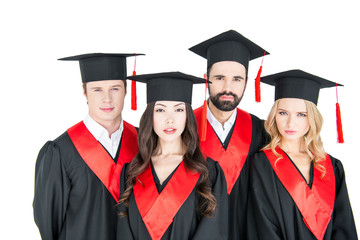 Group of young men and women in graduation caps looking at camera