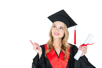 Beautiful young blonde woman in mortarboard holding diploma pointing away with finger