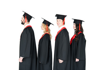 Smiling students in graduation caps standing in a row isolated on white