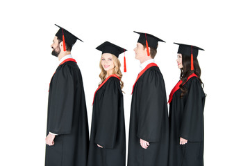 Smiling students in graduation caps standing in a row isolated on white