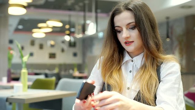 Beautiful businesswoman sitting in the cafe and texting on smartphone

