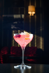 Barman at work, preparing cocktails. pouring cosmopolitan to cocktail glass.