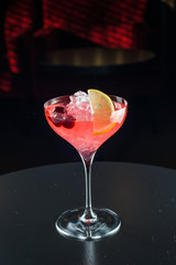 Barman at work, preparing cocktails. pouring cosmopolitan to cocktail glass.