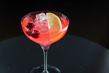 Barman at work, preparing cocktails. pouring cosmopolitan to cocktail glass.