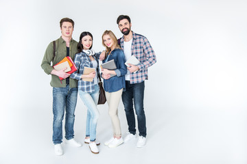 four young students in casual clothes holding books on white