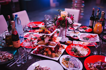 Dishes with delicacies and appetizers in red and white plates on a serving table