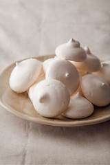 Homemade meringues on ceramic plate and linen fabric