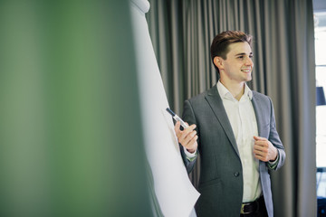 portrait of a confident businessman making presentation on flipchart in modern office