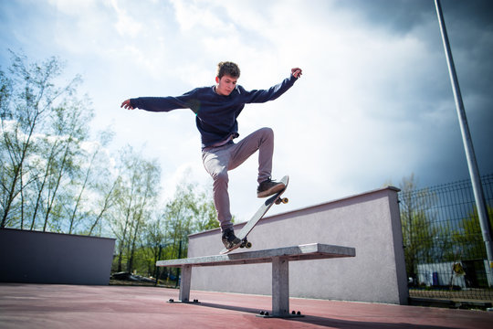 Skater doing blunt slide trick on bench in skatepark