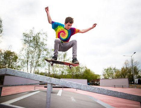 Skater jumping over handrail in skatepark