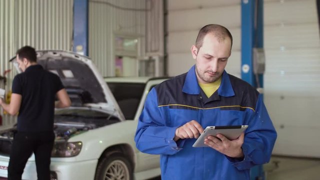 car mechanic using tablet touch screen on a car cepair service