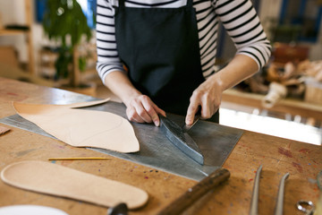 Close-up of shoemaker working on template in her workshop