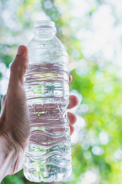 Man hand holding water bottle in park,selective focus.