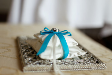 wedding rings on a cushion with blue ribbon