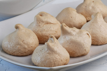 Meringues on white plate and light background