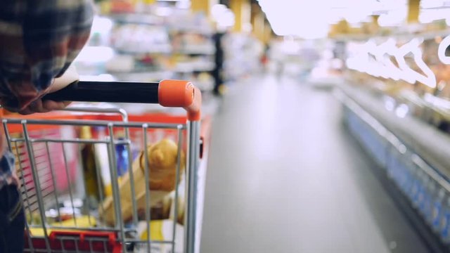 Cropped view of a man  walking in the supermarket and pushing shopping trolley