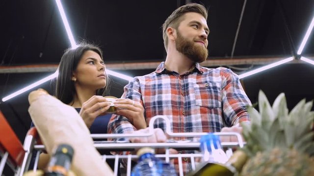 View from below of The woman is jealous of her boyfriend which walking in supermarket with shopping trolley