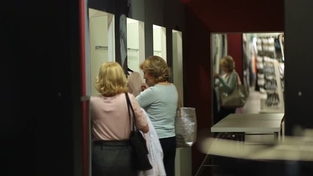 Happy shopaholic women entering fitting room